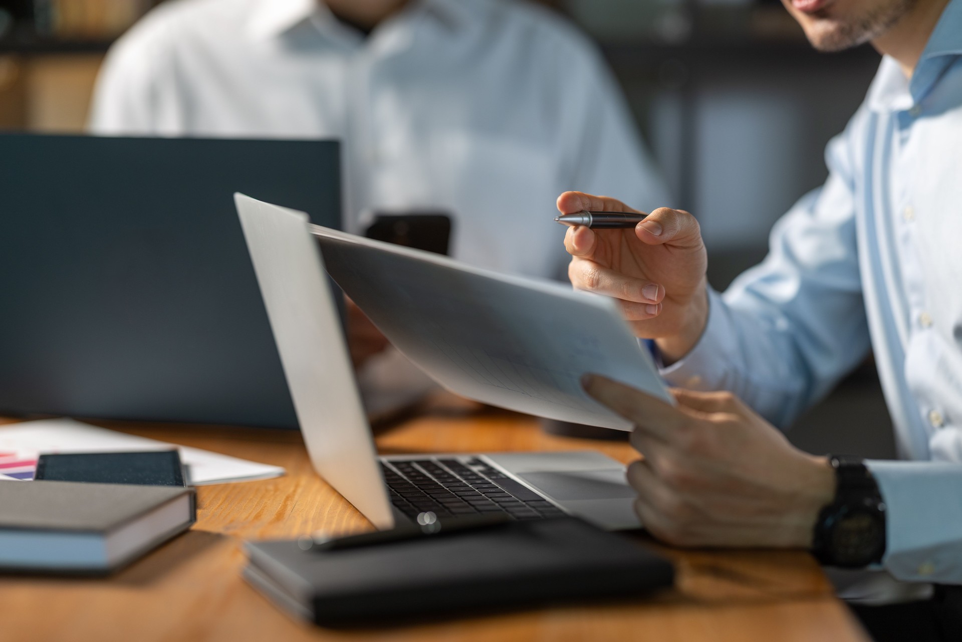 Businessman analyzing documents and working on laptop in office meeting